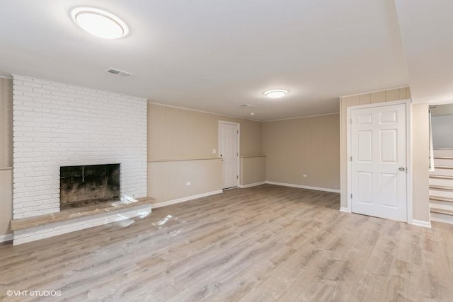 unfurnished living room featuring light wood-type flooring and a brick fireplace