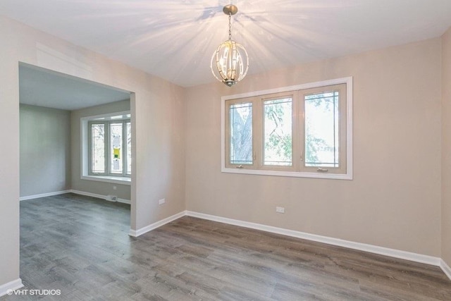 unfurnished room featuring hardwood / wood-style floors and an inviting chandelier