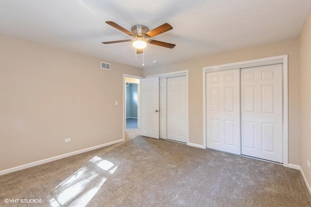 unfurnished bedroom featuring carpet flooring, multiple closets, and ceiling fan