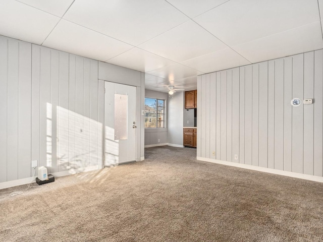 spare room with ceiling fan, carpet flooring, and wooden walls