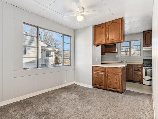 kitchen featuring stainless steel range, ceiling fan, light colored carpet, and sink