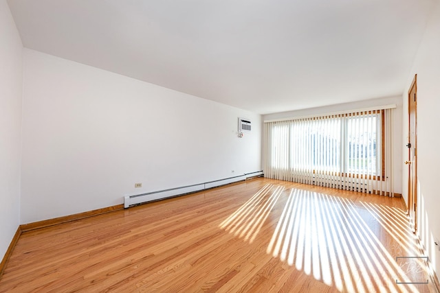 empty room featuring a wall mounted AC, a baseboard radiator, and light hardwood / wood-style flooring