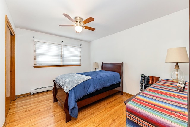 bedroom featuring a baseboard heating unit, ceiling fan, light hardwood / wood-style flooring, and a closet