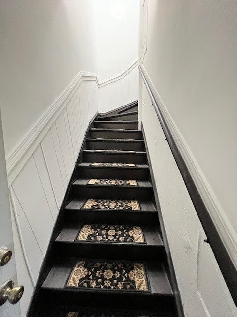 stairway with a decorative wall and a wainscoted wall