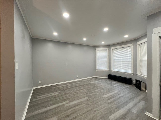 spare room with baseboards, ornamental molding, recessed lighting, radiator heating unit, and wood finished floors