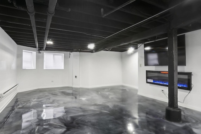 below grade area with baseboards, a glass covered fireplace, and baseboard heating