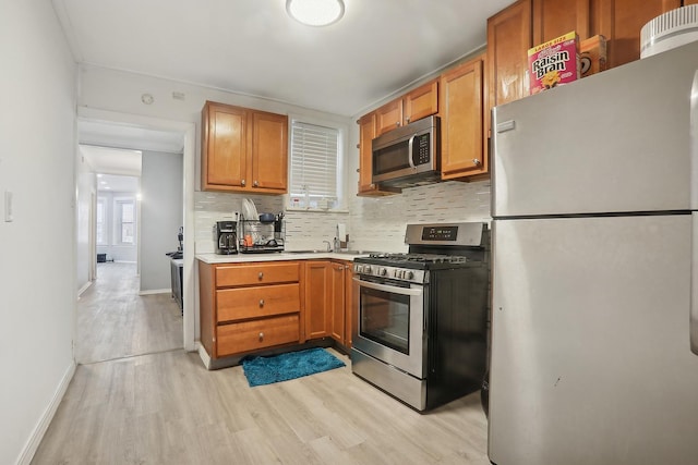 kitchen featuring decorative backsplash, stainless steel appliances, and light hardwood / wood-style flooring