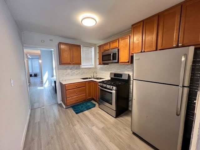 kitchen with brown cabinetry, light wood finished floors, light countertops, and stainless steel appliances
