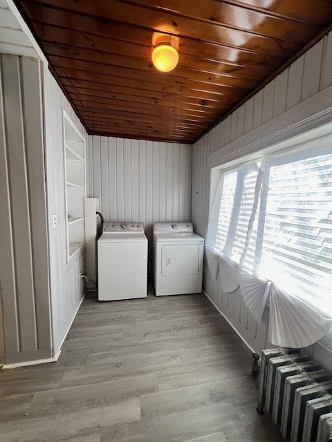 laundry area with radiator heating unit, washer and dryer, light wood finished floors, and laundry area
