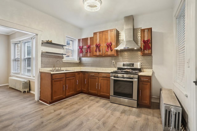 kitchen with radiator, sink, wall chimney exhaust hood, light hardwood / wood-style floors, and gas stove