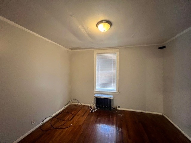 spare room with an AC wall unit, baseboards, ornamental molding, and wood finished floors