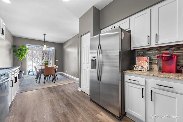 kitchen with backsplash, stainless steel appliances, decorative light fixtures, and white cabinets