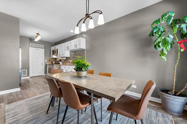 dining space featuring hardwood / wood-style flooring and an inviting chandelier