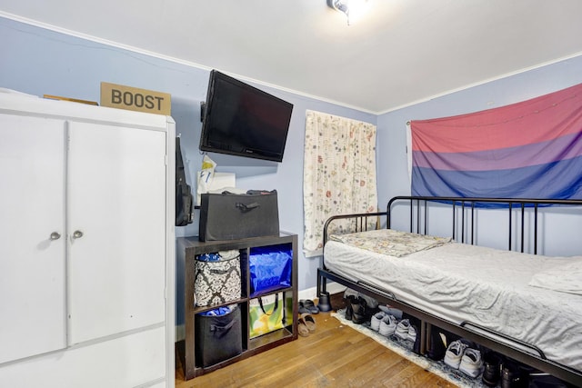 bedroom with wood-type flooring and ornamental molding