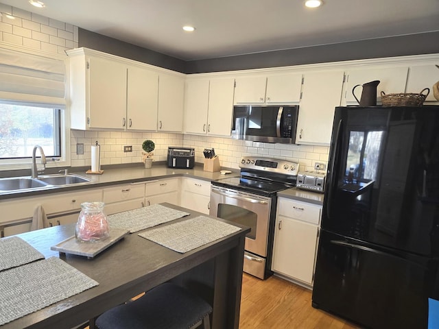 kitchen featuring appliances with stainless steel finishes, white cabinetry, decorative backsplash, sink, and light wood-type flooring