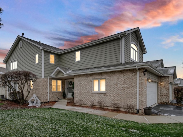 front of property featuring cooling unit, a yard, and a garage