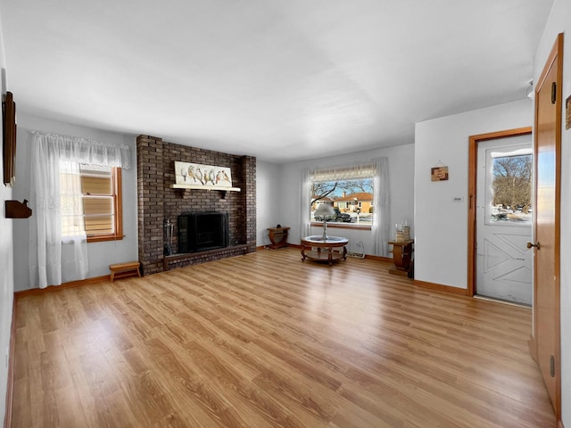 unfurnished living room featuring light wood-type flooring and a brick fireplace