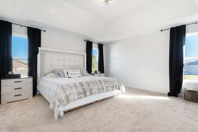 bedroom with light colored carpet, lofted ceiling, and multiple windows