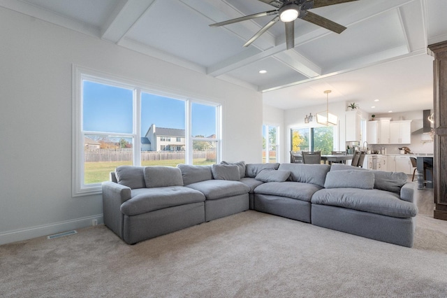 carpeted living room featuring ceiling fan, beamed ceiling, a healthy amount of sunlight, and coffered ceiling