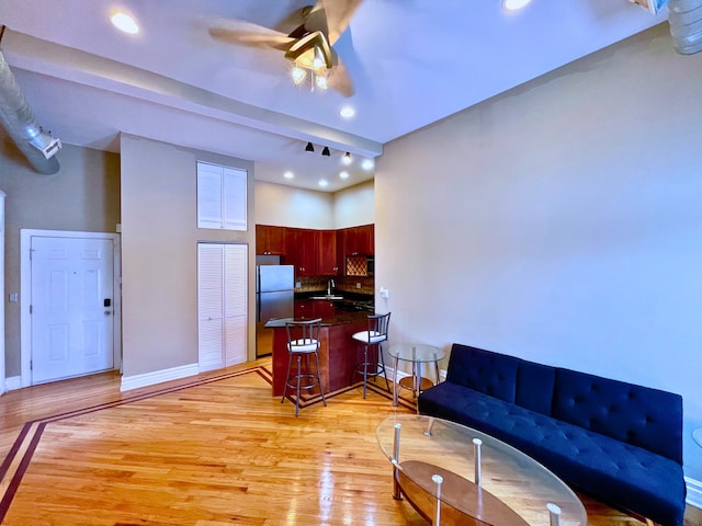 living room featuring ceiling fan, sink, and light hardwood / wood-style flooring