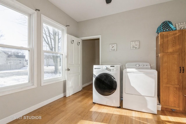 clothes washing area with light hardwood / wood-style flooring and washing machine and dryer