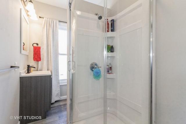 bathroom featuring vanity, wood-type flooring, and a shower with door