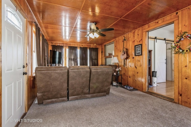 unfurnished living room with a barn door, carpet floors, wooden ceiling, and wood walls