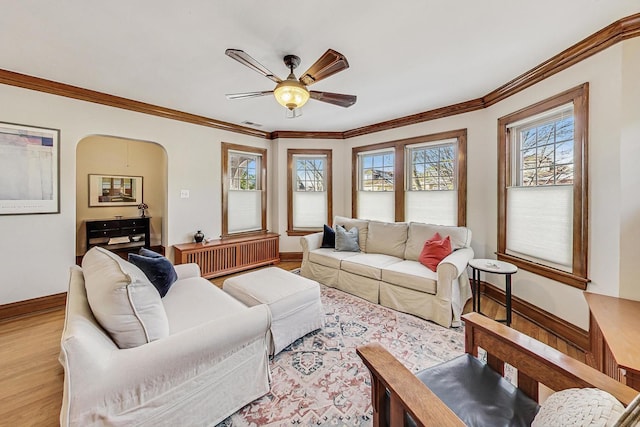 living room with light wood-type flooring, ceiling fan, and crown molding