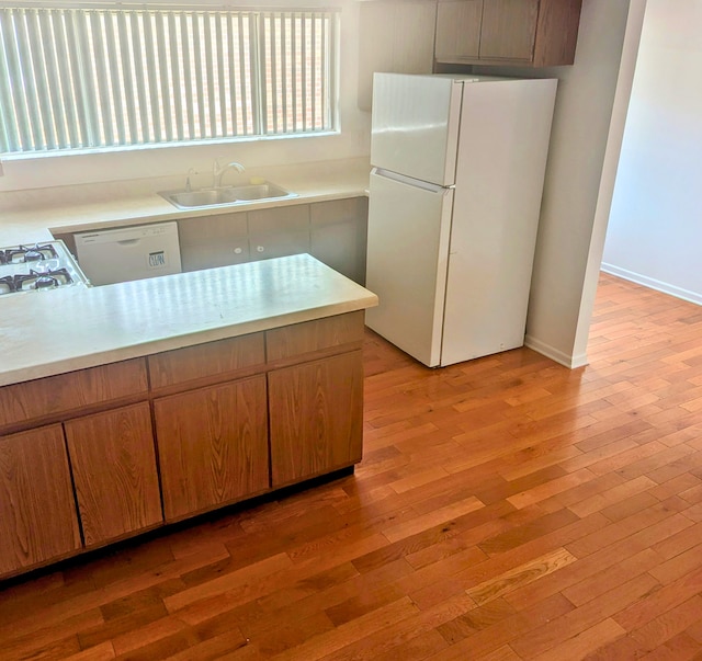 kitchen featuring sink, white appliances, and light wood-type flooring