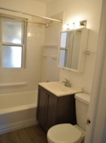 full bathroom with vanity, toilet, wood-type flooring, and shower / tub combination