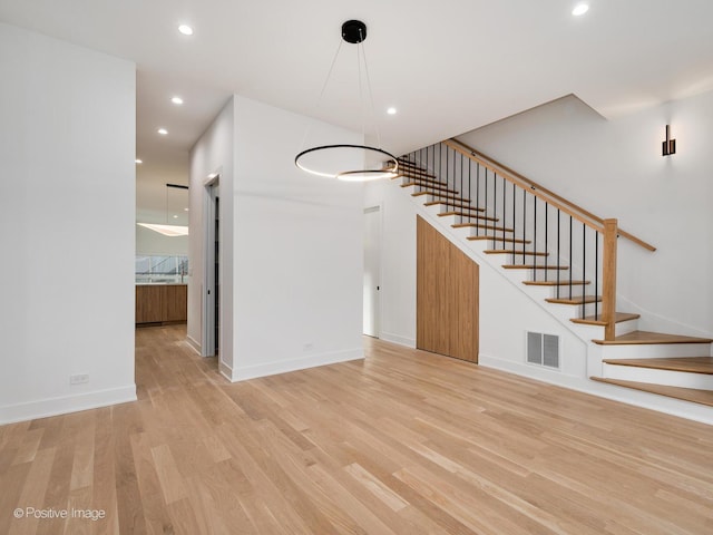 unfurnished living room with light hardwood / wood-style floors and an inviting chandelier