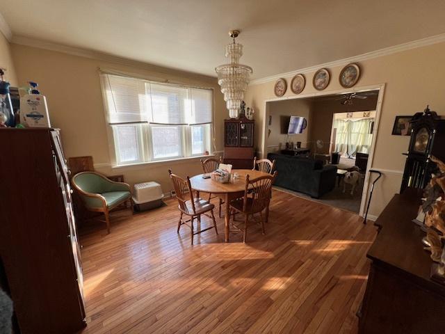 dining area with a chandelier, ornamental molding, and hardwood / wood-style floors