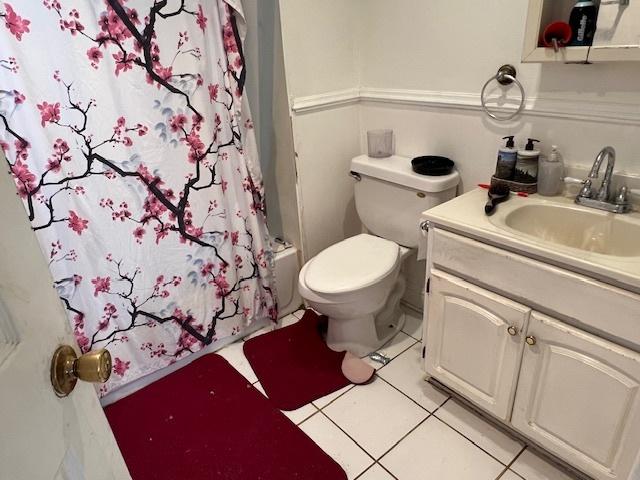 full bathroom featuring toilet, vanity, tile patterned floors, and shower / bath combination with curtain