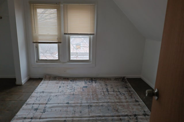 additional living space featuring tile patterned floors and lofted ceiling