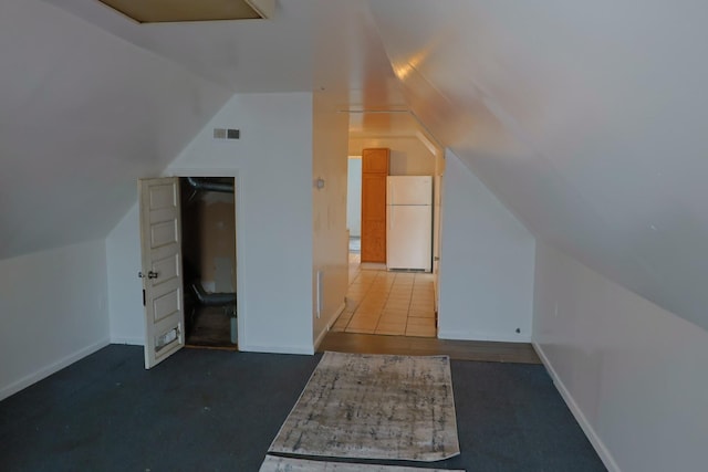 additional living space featuring dark carpet and lofted ceiling