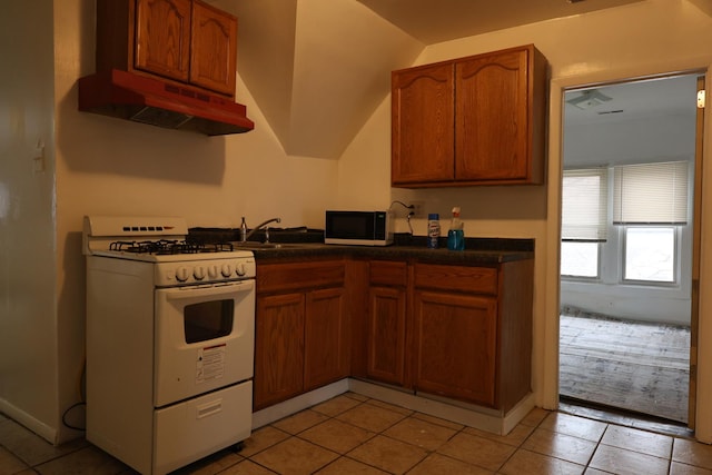 kitchen featuring light tile patterned floors, white gas stove, and sink