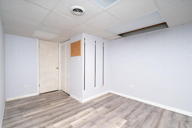 basement with a paneled ceiling and light hardwood / wood-style floors