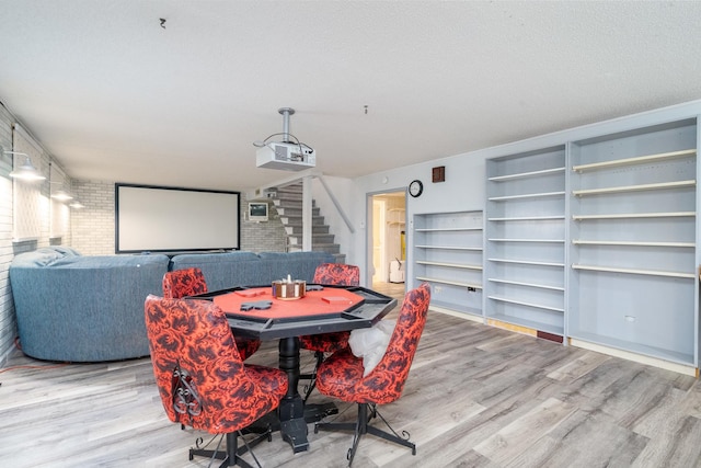 dining space featuring hardwood / wood-style flooring, a textured ceiling, and brick wall