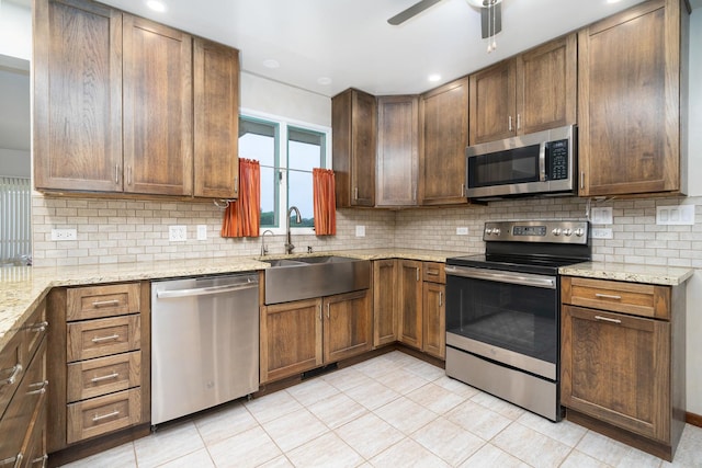 kitchen featuring light stone countertops, sink, stainless steel appliances, backsplash, and light tile patterned floors