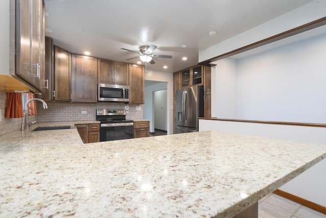 kitchen featuring ceiling fan, sink, stainless steel appliances, backsplash, and kitchen peninsula