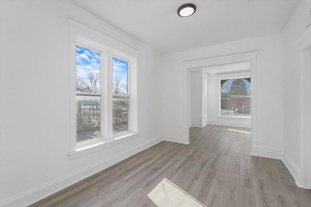 unfurnished dining area featuring light wood-type flooring, a wealth of natural light, and crown molding