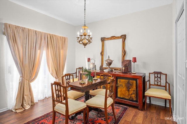 dining room with dark wood-type flooring and an inviting chandelier