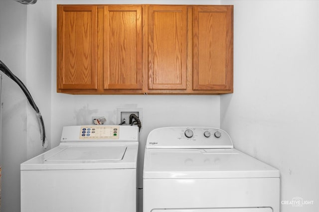 clothes washing area featuring cabinets and independent washer and dryer