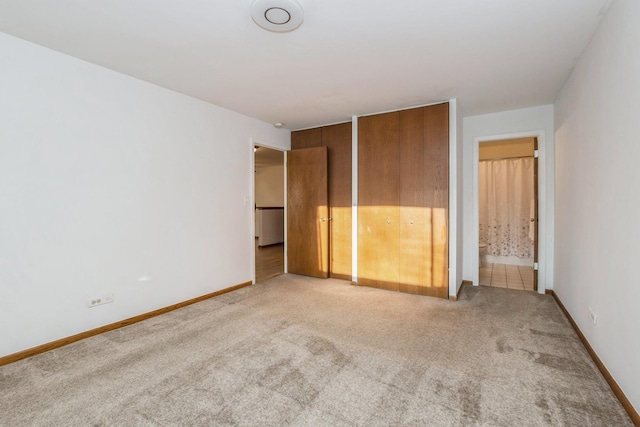 unfurnished bedroom featuring ensuite bath and light carpet