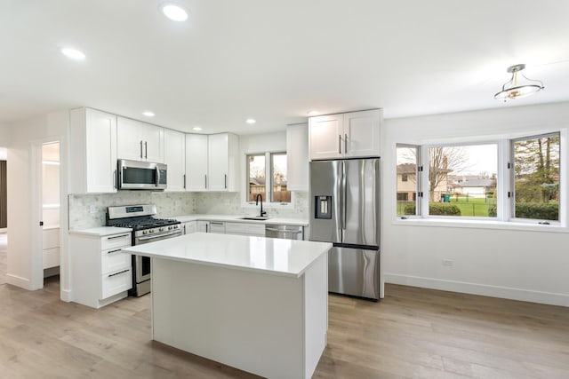 kitchen with a wealth of natural light, white cabinets, light wood-type flooring, and appliances with stainless steel finishes