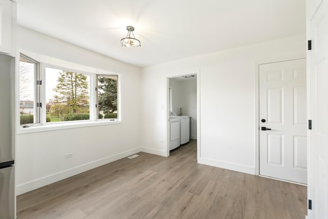 unfurnished bedroom featuring washing machine and dryer and light hardwood / wood-style flooring