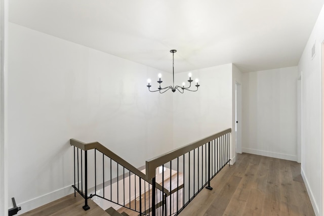 hall with hardwood / wood-style floors and a notable chandelier