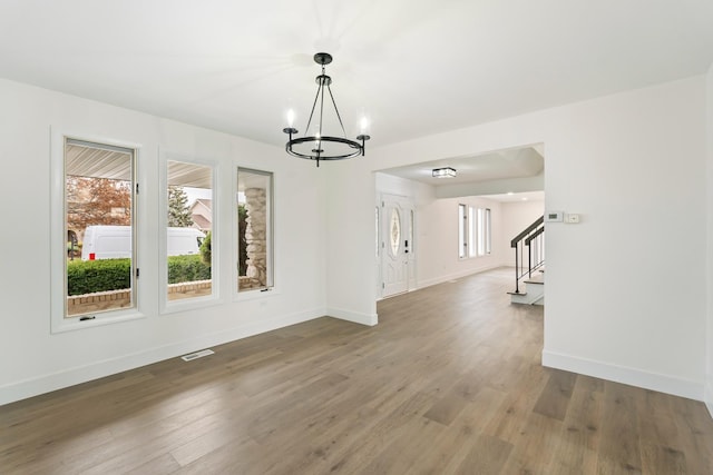 unfurnished dining area featuring wood-type flooring and a notable chandelier