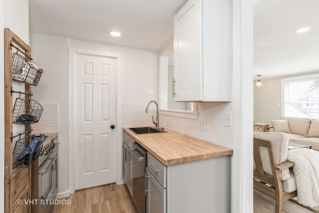 kitchen with sink, wooden counters, dishwasher, white cabinetry, and light hardwood / wood-style floors