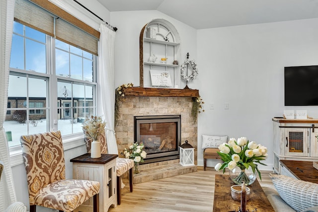 sitting room featuring vaulted ceiling, a fireplace, and light hardwood / wood-style floors